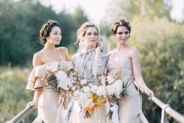 Çiçek ve dekorla düğün kemerinin önünde güzel bir gelin. Buket ellerde ve detaylarda. Kız mutlu, gülümsüyor ve dans ediyor. Modern tarzda bir gelinlik hayal et.