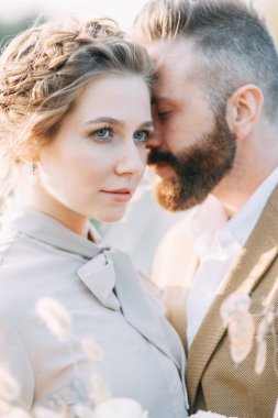 Toplantı yeni evliler köprüde güzel kisses ve hugs. Gün batımında düğün doğada. Tören için iki. Şık modern düğün. Gelin buketi ve dekor.
