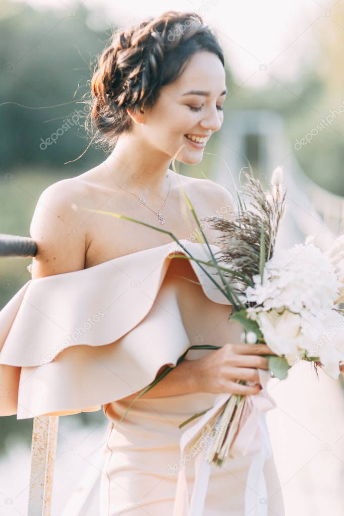 Beautiful bride in front of wedding arch with flowers and decor. Bouquet in the hands and details. The girl is happy, smiling and dancing. Dream wedding dress in modern style