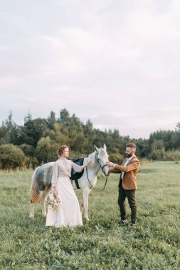 Düğün Amerikan tarzı, bir at ile bir çiftlikte. Çiftler batımında, arkadaş grubu ve sırtında tarlada yürümek. Modern çift ve tören için fikirler.