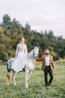 Düğün Amerikan tarzı, bir at ile bir çiftlikte. Çiftler batımında, arkadaş grubu ve sırtında tarlada yürümek. Modern çift ve tören için fikirler.