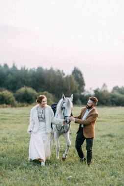 Düğün Amerikan tarzı, bir at ile bir çiftlikte. Çiftler batımında, arkadaş grubu ve sırtında tarlada yürümek. Modern çift ve tören için fikirler.