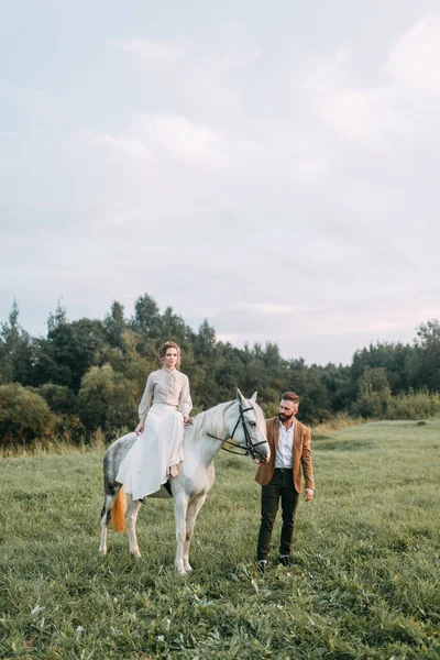 馬と牧場のアメリカン スタイルの結婚式 友人とは馬に乗って 夕暮れ時のカップルのフィールドで歩いてください モダンなカップルは 式のためのアイデア — ストック写真