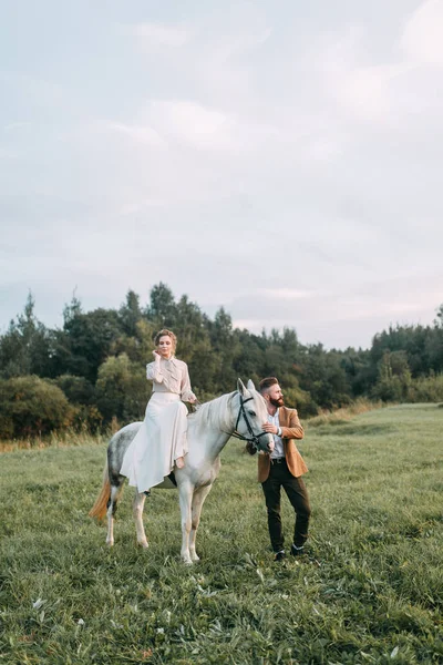 馬と牧場のアメリカン スタイルの結婚式 友人とは馬に乗って 夕暮れ時のカップルのフィールドで歩いてください モダンなカップルは 式のためのアイデア — ストック写真