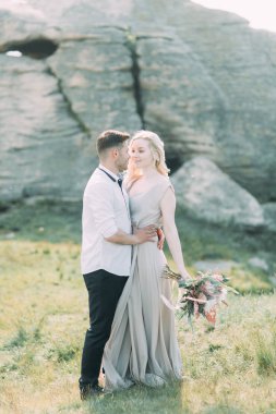 Düğün çifti bir yürüyüş, fotoğraf çekimi dağlarda. Dekor güzel sanatlar tarzında. Şık genç manken