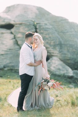 Düğün çifti bir yürüyüş, fotoğraf çekimi dağlarda. Dekor güzel sanatlar tarzında. Şık genç manken