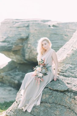 Doğada, dağlarda gelin. Düğün güzel sanatlar tarzında. Dağlar ve boudoir elbiseli günbatımı.