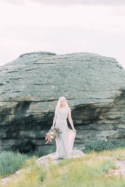 Bride in nature, in the mountains. Wedding in the style of fine art. The mountains and the sunset in the boudoir dress.