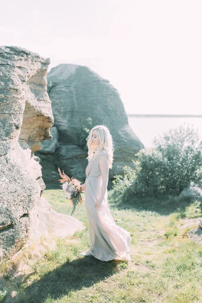 Bride in nature, in the mountains. Wedding in the style of fine art. The mountains and the sunset in the boudoir dress.