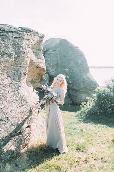 Bride in nature, in the mountains. Wedding in the style of fine art. The mountains and the sunset in the boudoir dress.