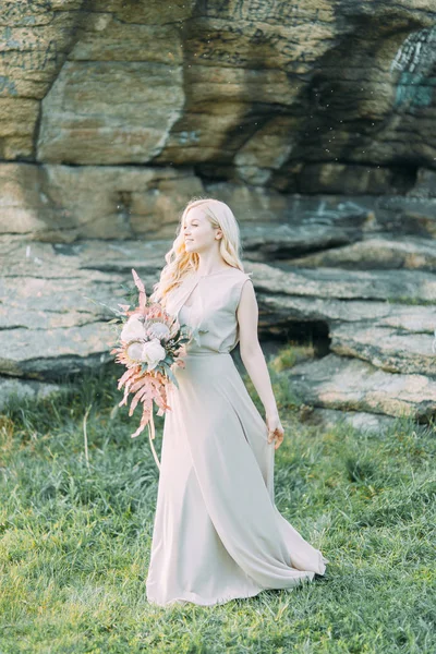 Bride in nature, in the mountains. Wedding in the style of fine art. The mountains and the sunset in the boudoir dress.