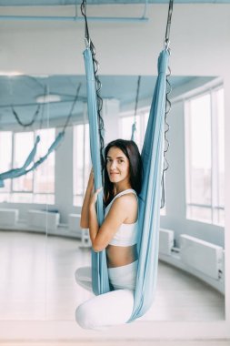 Oturma ve eğitim gülümseyen güzel kız. Rahatlamak ve gevşemek yoga hamak. 