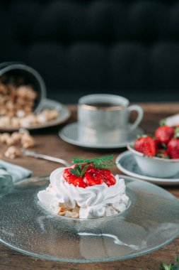 Pavlova tatlı güzel bir kompozisyon içinde çilek ile. Foodstyling kahve ve çilek ahşap bir zemin üzerine.