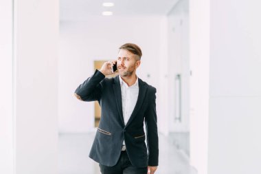 İşadamı ofis telefon aramaları ve çalışmaya gider. Gülümseme ve duygular çalışırken.