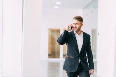 İşadamı ofis telefon aramaları ve çalışmaya gider. Gülümseme ve duygular çalışırken.