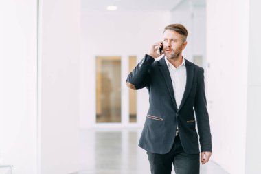 İşadamı ofis telefon aramaları ve çalışmaya gider. Gülümseme ve duygular çalışırken.