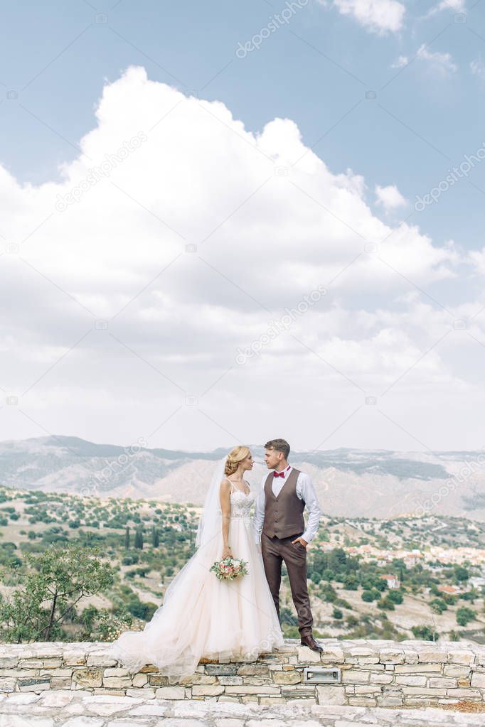 Wedding couple in the mountains at sunset in Cyprus. Beautiful panoramic view and the happy couple.