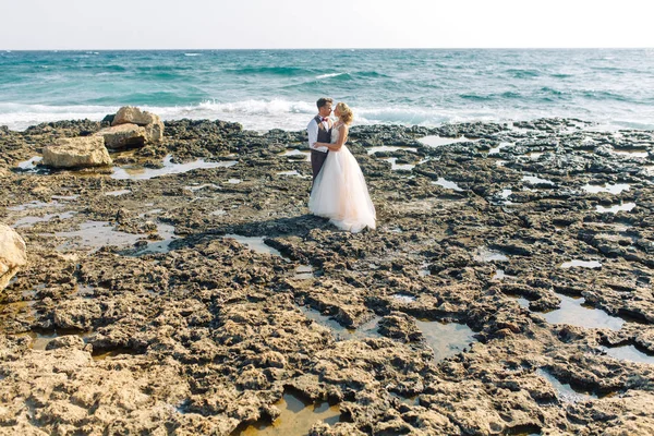 ビーチで結婚式の写真撮影 夕暮れ時のカップルが歩くし 笑いとキス — ストック写真