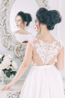 Gelin bir buket ile parlak bir stüdyoda. Gelinlik ve ayna.