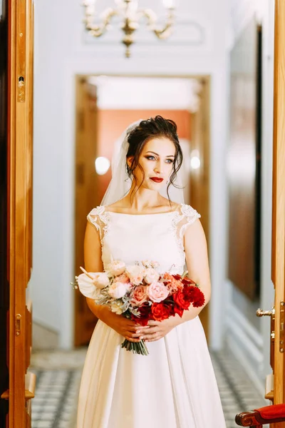 The bride in an expensive luxury hotel with a bouquet. Standing on the stairs and in the hallway.