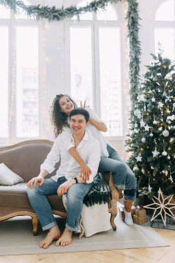 Bir kucaklama içinde kanepede yatan genç bir çift. Yeni yıl için parlak bir iç stüdyoda fotoğraf çekimi.