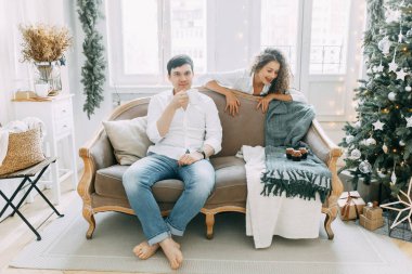 Bir kucaklama içinde kanepede yatan genç bir çift. Yeni yıl için parlak bir iç stüdyoda fotoğraf çekimi.