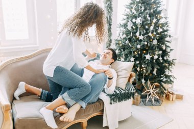 Bir kucaklama içinde kanepede yatan genç bir çift. Yeni yıl için parlak bir iç stüdyoda fotoğraf çekimi.