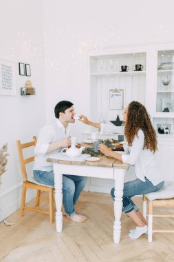 Genç çift tatlılar yemek masada. Yeni yıl için parlak bir iç stüdyoda fotoğraf çekimi.