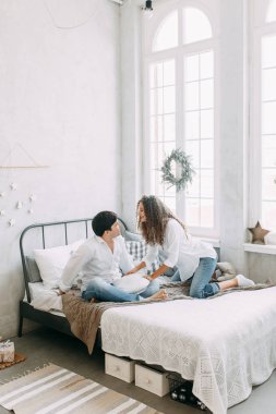 Genç çift, sarılma ve yatağın değil mücadele. Avrupa tarzı parlak iç stüdyo fotoğraf çekimi.