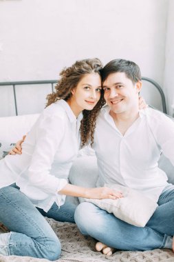 Genç çift, sarılma ve yatağın değil mücadele. Avrupa tarzı parlak iç stüdyo fotoğraf çekimi.