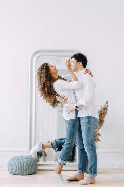 Genç kucaklayan ve bir ayna önünde oturan çift. Avrupa tarzı parlak iç stüdyo fotoğraf çekimi.