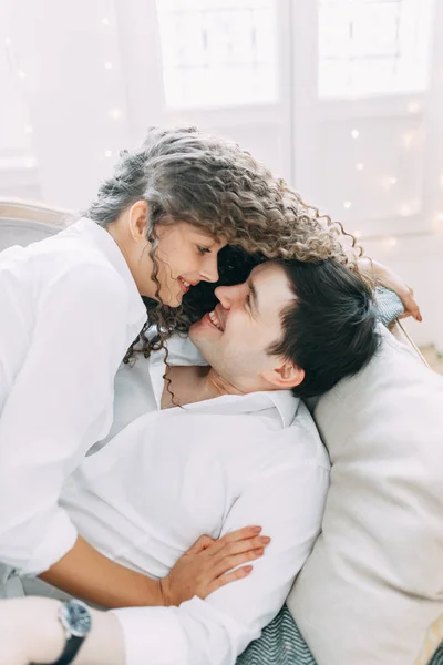 抱擁のソファに横になっている若いカップル 新年の明るいインテリア スタジオでの写真撮影 — ストック写真