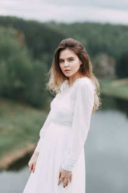 Beyaz elbiseli doğada Boudoir sabah gelin. Serisi kayalıklarla ve nehir üzerinde düğün virajlı.