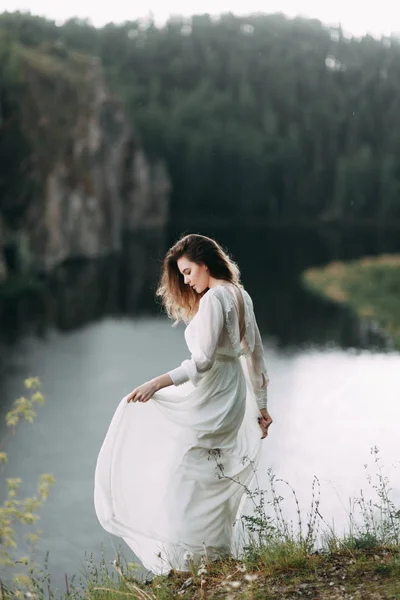 Beyaz elbiseli doğada Boudoir sabah gelin. Serisi kayalıklarla ve nehir üzerinde düğün virajlı.