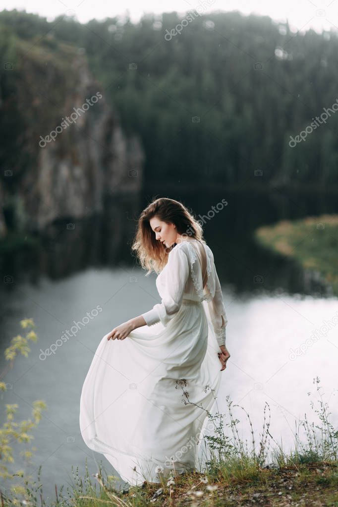 Boudoir morning bride in nature in a white dress. Wedding series on cliffs and river bends.