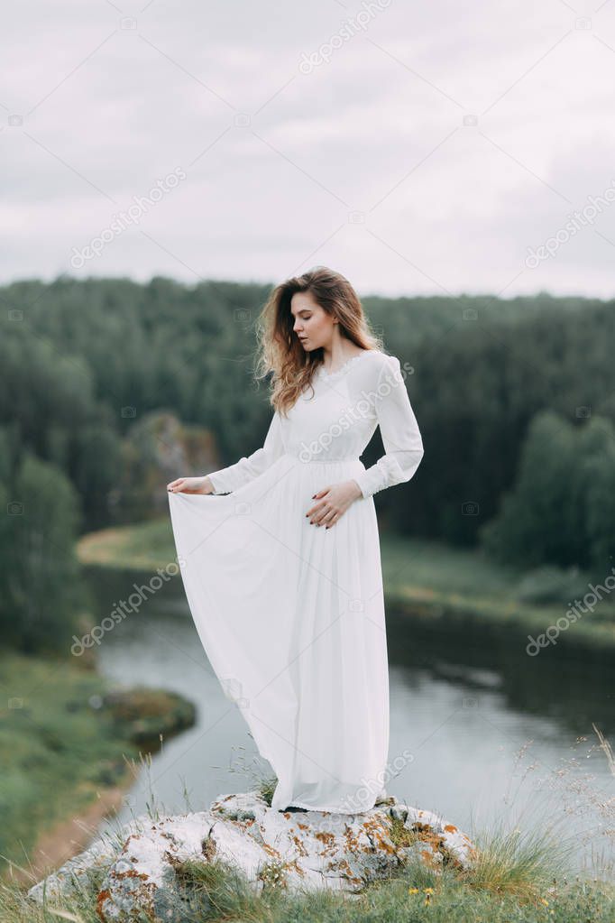 Boudoir morning bride in nature in a white dress. Wedding series on cliffs and river bends.