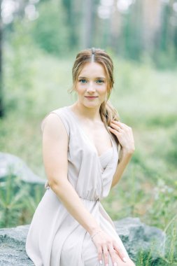 Boudoir photo shoot of the bride in the woods with a bouquet. Flying dress and beautiful girl in the Park.