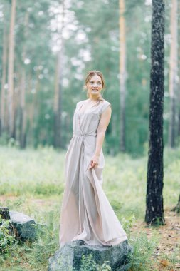 Boudoir photo shoot of the bride in the woods with a bouquet. Flying dress and beautiful girl in the Park.