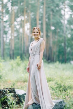 Boudoir photo shoot of the bride in the woods with a bouquet. Flying dress and beautiful girl in the Park.