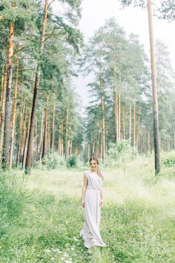 Boudoir photo shoot of the bride in the woods with a bouquet. Flying dress and beautiful girl in the Park.