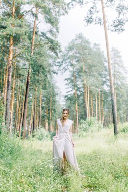 Boudoir photo shoot of the bride in the woods with a bouquet. Flying dress and beautiful girl in the Park.