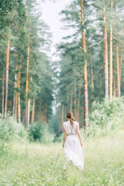 Boudoir photo shoot of the bride in the woods with a bouquet. Flying dress and beautiful girl in the Park.