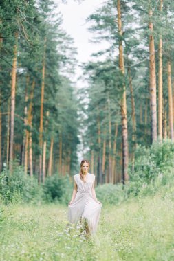 Boudoir photo shoot of the bride in the woods with a bouquet. Flying dress and beautiful girl in the Park.