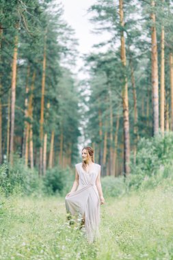 Boudoir photo shoot of the bride in the woods with a bouquet. Flying dress and beautiful girl in the Park.