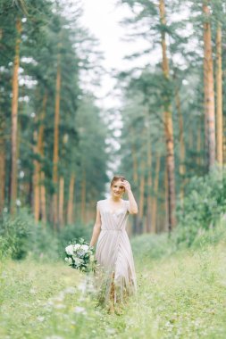 Boudoir photo shoot of the bride in the woods with a bouquet. Flying dress and beautiful girl in the Park.