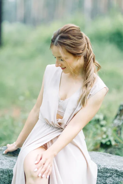 Boudoir photo shoot of the bride in the woods with a bouquet. Flying dress and beautiful girl in the Park.