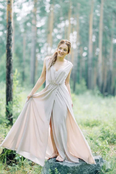 Boudoir photo shoot of the bride in the woods with a bouquet. Flying dress and beautiful girl in the Park.