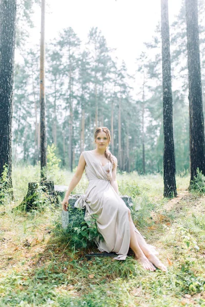 Boudoir photo shoot of the bride in the woods with a bouquet. Flying dress and beautiful girl in the Park.