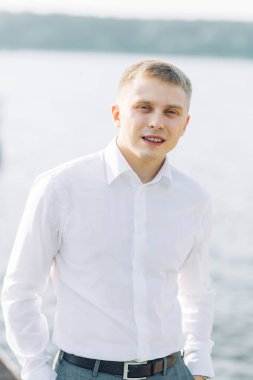 Doğada su damat. Toplantıda genç bir adamın iskelede günbatımı.