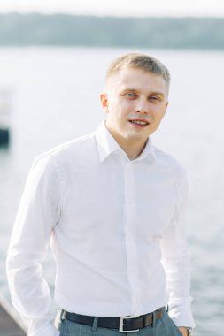 Doğada su damat. Toplantıda genç bir adamın iskelede günbatımı.